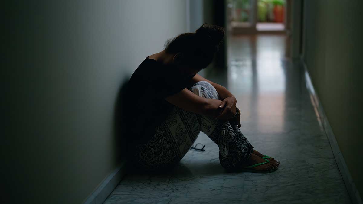 Middle age hispanic woman suffering for domestic violence with bruise on eyes sitting on floor at home